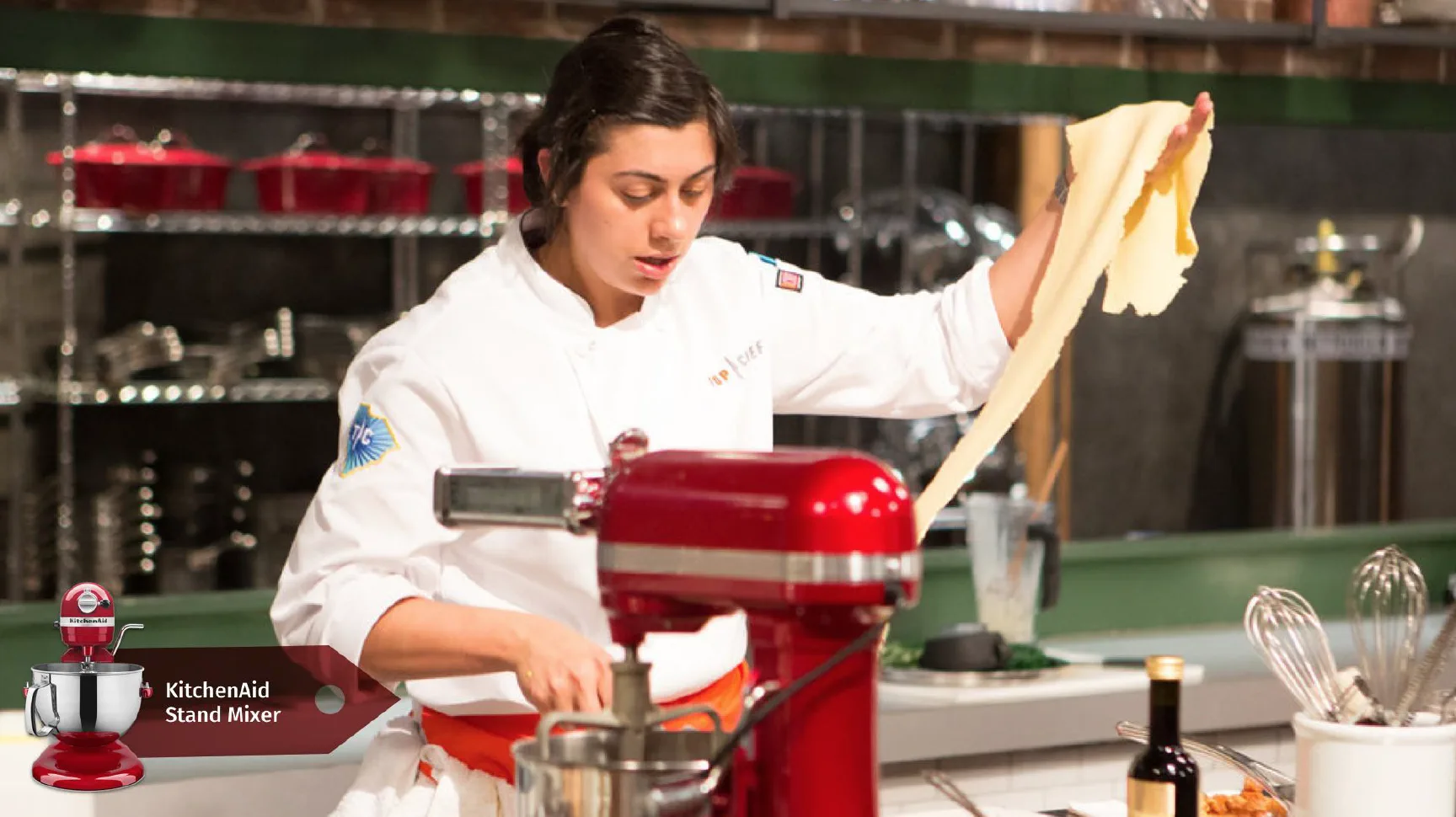 Chef working with pasta dough using a red KitchenAid stand mixer.